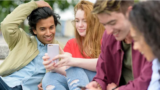 スマートフォンで情報を共有する笑顔の若者たち