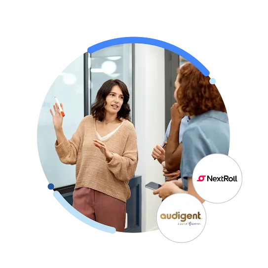 A woman illustrates concepts on a whiteboard while a group of people attentively listens and engages, with a NextRoll and Audigent logo.