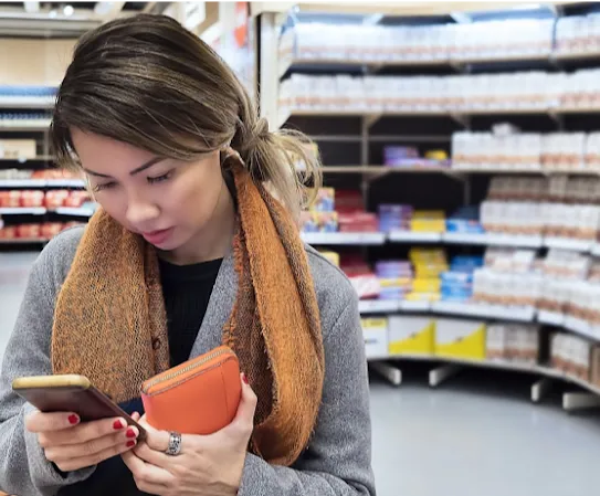 買い物中にスマートフォンでニュースをチェックしている女性